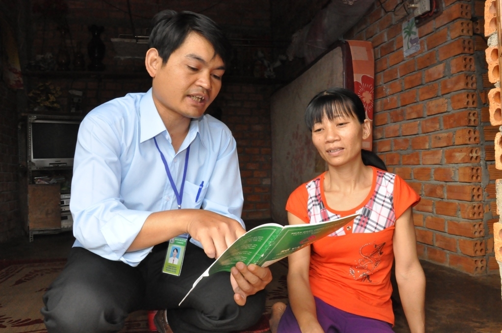 Cán bộ tín dụng NHCSXH hướng dẫn thủ tục vay hộ cận nghèo cho một hộ dân tại huyện Cư Kuin 