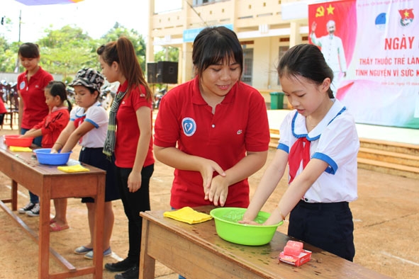 Tình nguyện viên hướng dẫn các em học sinh Trường TH Nơ Trang Lơng rửa tay bằng xà phòng.