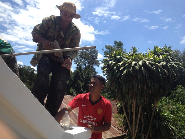 Anh Y D’Hiăm Niê (phải) đang hướng dẫn thợ hoàn thiện phần mái của một ngôi nhà ở buôn Cuôr Đăng B.