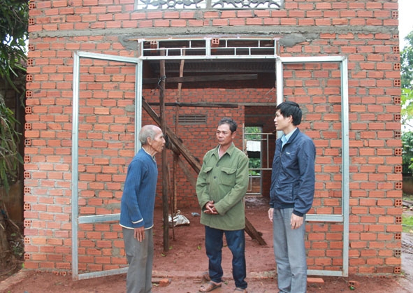 Cán bộ giảm nghèo xã Cư Ni và ban tự quản buôn Ea Păl thăm hỏi tiến độ xây dựng nhà của gia đình ông Y Đring Niê (bên trái). 
