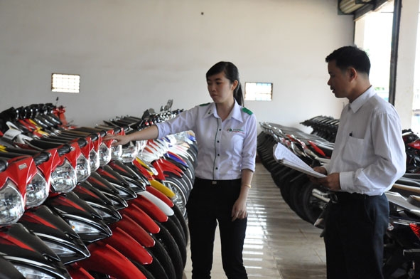 Nhân viên một tổ chức tài chính giới thiệu sản phẩm tại cửa hàng xe gắn máy ở huyện Cư Kuin.