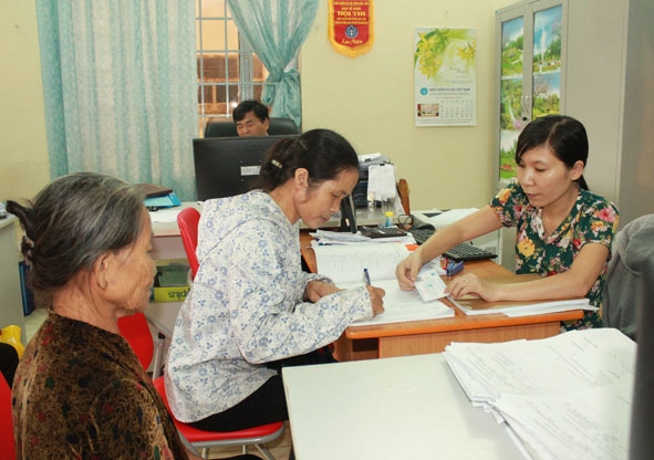 Nhân viên Bộ phận tiếp nhận và trả kết quả BHXH huyện M'Đrắk cấp đổi thẻ BHYT cho người dân.   Ảnh: N. Xuân