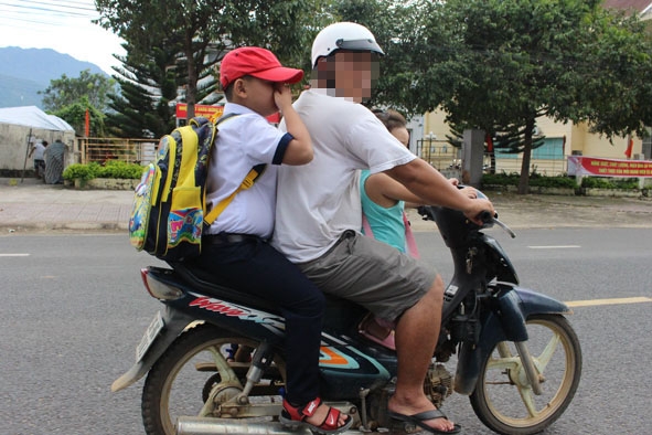 Một phụ huynh không đội MBH cho trẻ khi tham gia giao thông. 