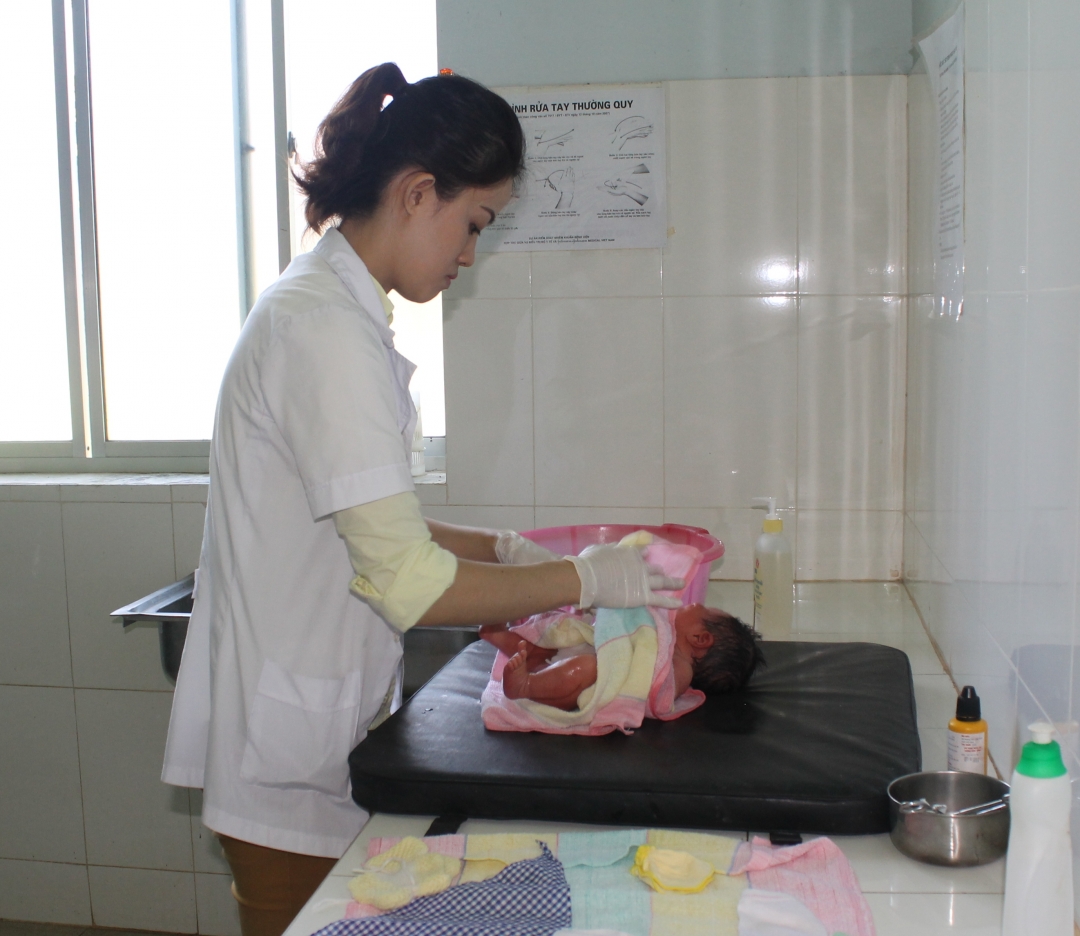 Cán bộ trạm y tế xã Hòa Xuân tắm cho trẻ sơ sinh. 