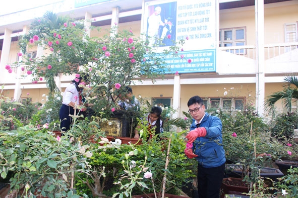 Thầy Nguyễn Tiến Lâm cùng các em học sinh Trường Tiểu học Nguyễn Đức Cảnh (TP. Buôn Ma Thuột)  chăm sóc vườn hồng trong sân trường. 