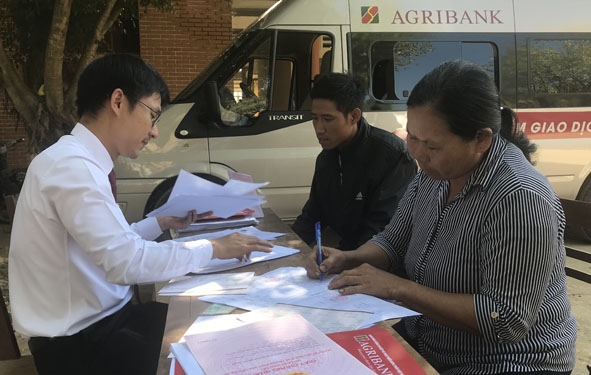 Người dân xã Buôn Triết (huyện Lắk) làm thủ tục vay vốn qua điểm giao dịch lưu động bằng xe ô tô chuyên dụng của Agribank Đắk Lắk.