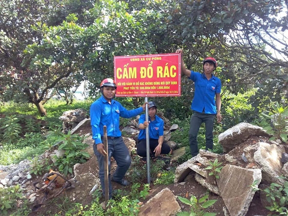 Anh Y Hlý Niê Kdăm (trái) cùng đoàn viên thanh niên  xã Cư Pơng cắm biển cấm đổ rác bừa bãi. 