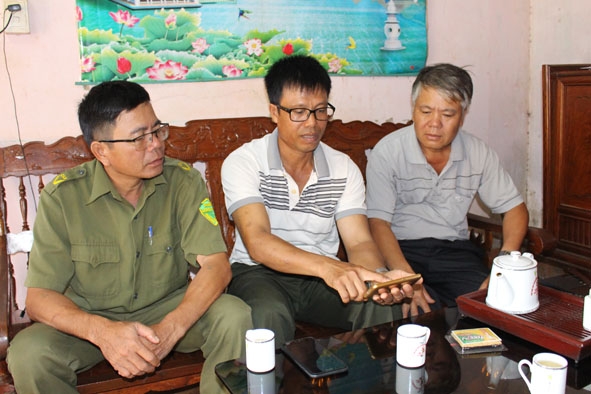 Ông Mai Ngọc Toản,  Bí thư Chi bộ thôn 3, xã Tân Lập (người ngồi giữa) theo dõi hoạt động của camera an ninh qua điện thoại di động. 