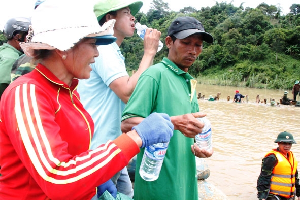 Chị Trần Thị Hải tiếp nước uống cho người dân tham gia hộ đê cứu lúa.  