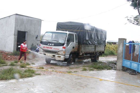 Xịt khử trùng xe chở thức ăn cho heo tại trang trại hộ anh Nguyễn Văn Phước.  