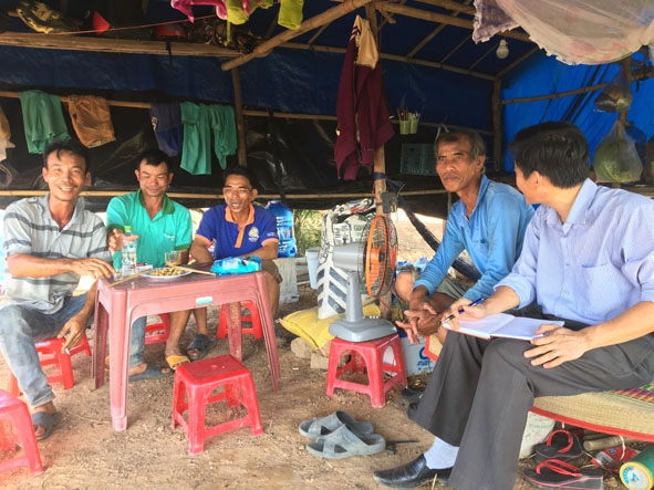 Ông Võ Văn Vân (thứ hai từ phải sang) cùng một số chủ ruộng dưa trò chuyện với phóng viên trong túp lều tuềnh toàng tạm bợ.    Ảnh: Trọng Khang