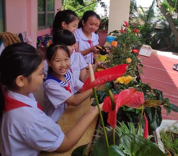 Học sinh Trường Tiểu học Nguyễn Công Trứ chăm sóc vườn hoa. 