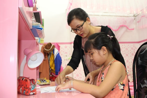 Chị Trần Thị Xuân Quỳnh  ở thị trấn Phước An hướng dẫn  con làm bài tập ở nhà. 