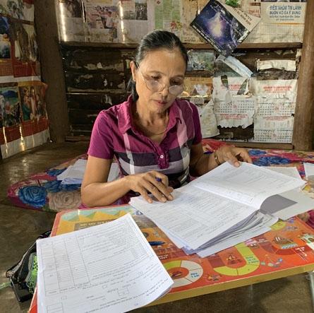 Bà H' Blẽn Byă đang rà soát danh sách hộ nghèo  của buôn.  