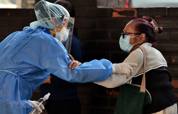 Nhân viên y tế giúp đỡ một bệnh nhân nhiễm Covid-19 tại bệnh viện ở Tegucigalpa, Honduras.   Ảnh: AFP/TTXVN