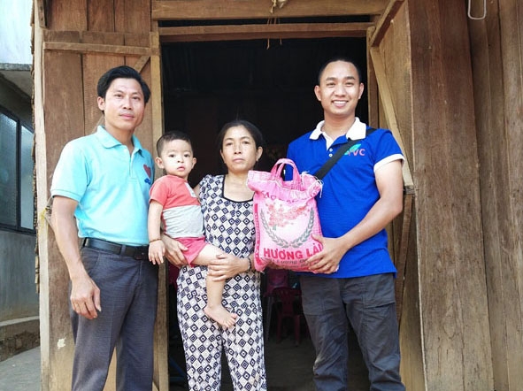 Anh Thân Văn Bình (bìa phải) tặng quà gia đình em Nguyễn Đức Mạnh ở xã Ea Na, huyện Krông Ana.    