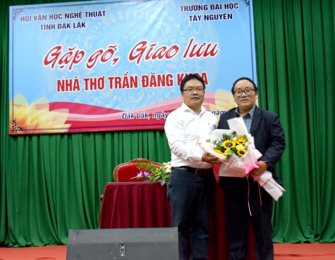 Đại diện Trường Đại học Tây Nguyên tặng hoa cho nhà thơ Trần Đăng Khoa. Ảnh: Đ.Dũng
