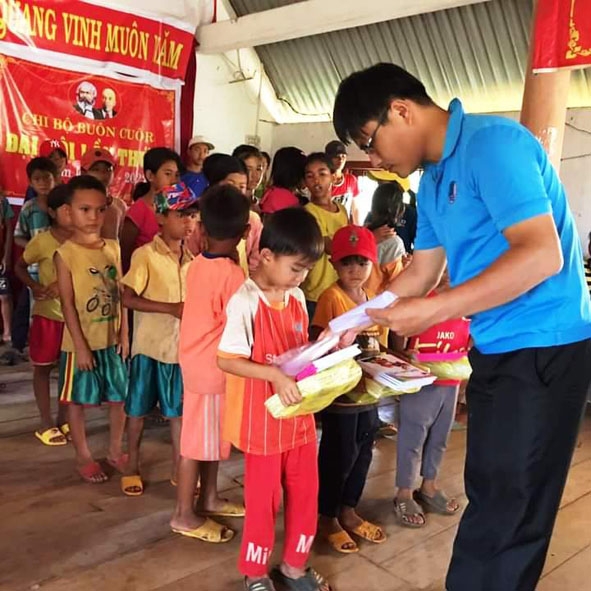 Thầy Mai Văn Chuyền tặng sách vở  cho học sinh của xã  Ea M'droh. 