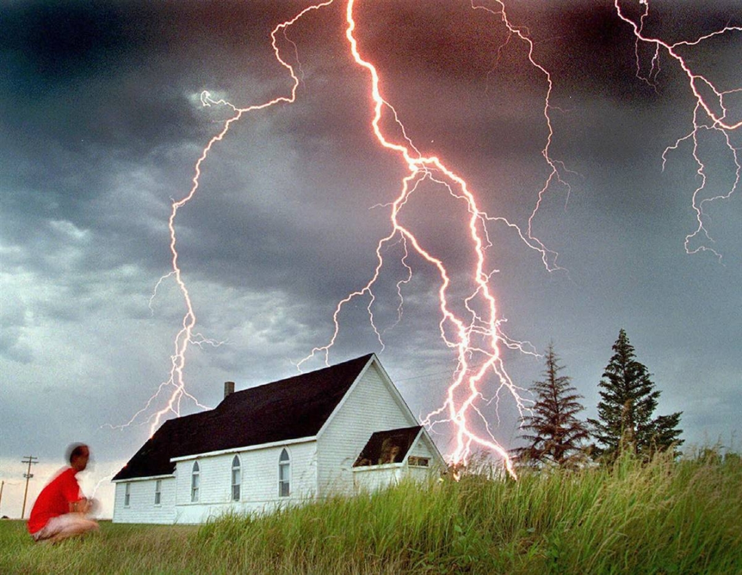 Anh Neil Fraser đang ngồi ngắm nghía nhưng tia sét đánh bên ngoài một nhà thờ ở Rosser, Manitoba, vào buổi sáng chủ nhật ngày 30-71995. (AP) 