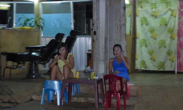 Hai tiếp viên hớt tóc nam ăn mặc khêu gợi ngồi chờ khách trên đường Lê Thị Hồng Gấm.