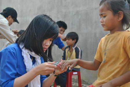 Tình nguyện viên bấm móng tay cho các em nhỏ