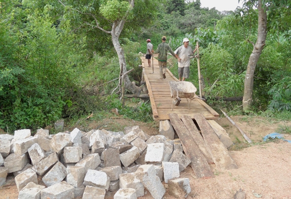 Người dân đang làm cầu gỗ bắc qua suối ở thôn I xã Cư Drăm.