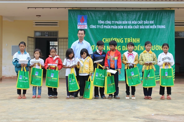 Đại diện Công ty Phân bón và Hóa chất dầu khí miền Trung trao quà cho các em học sinh.