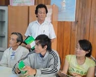 Ông Trần Hữu Thưởng (đứng phía sau) đang hướng dẫn  thành viên nhóm Tiếp cận cộng đồng cách tuyên truyền  phòng chống HIV/AIDS.