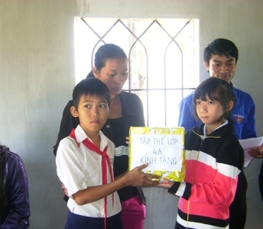   Em Ngô  Văn Bình  (trái) nhận  quà tặng của  các bạn  học sinh trong  ngôi nhà mới.