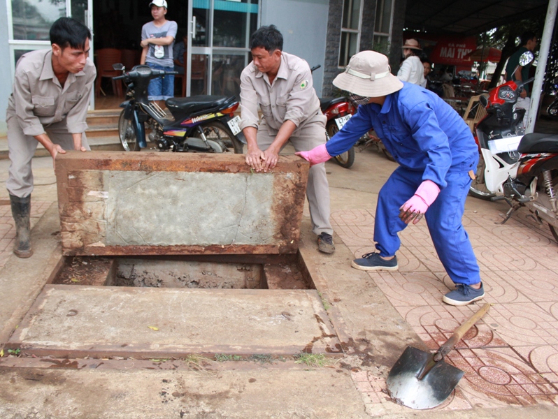 Để mở nắp hố ga, các công nhân phải dùng xà beng cạy rồi tập trung nhiều người nâng lên 