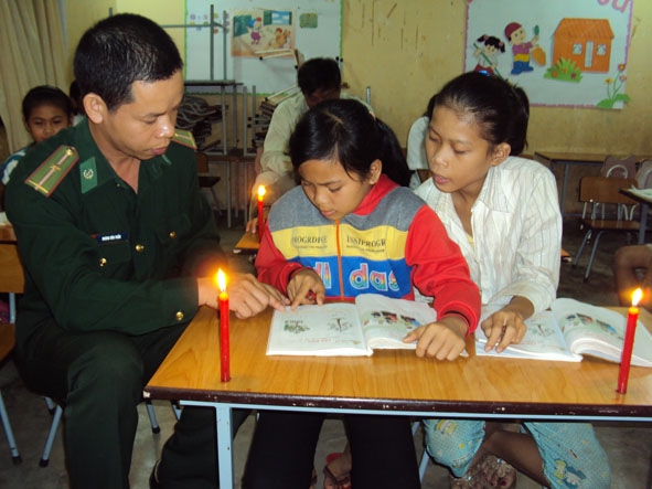 Những thầy giáo mang quân hàm xanh đang tận tình hướng dẫn các học sinh  tham gia lớp học xóa mù chữ.