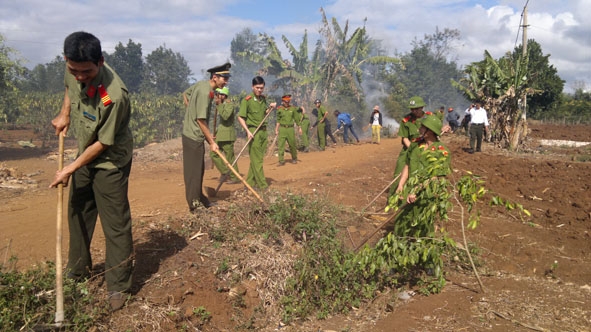 Cán bộ, chiến sĩ Công an thị xã Buôn Hồ tham gia phát dọn  vệ sinh môi trường tại buôn kết nghĩa Ea Kjoh A (xã Ea Drông).