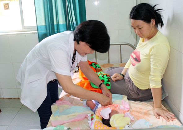 Nữ hộ sinh Trần Thị Huệ chăm sóc sức khỏe cho mẹ và bé sau sinh  tại Trạm Y tế phường Khánh Xuân.