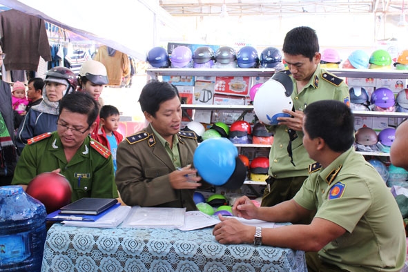 Kiểm tra mặt hàng mũ  bảo hiểm được  bày bán tại một  hội chợ diễn ra ở thị xã Buôn Hồ.