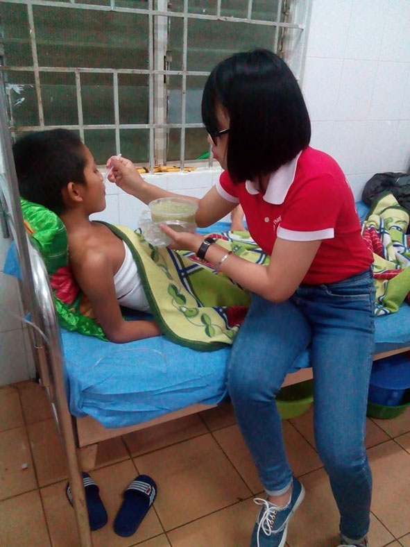 Một tình nguyện viên chăm sóc em Vương Văn Thanh đang điều trị bỏng  tại Bệnh viện Đa khoa tỉnh.