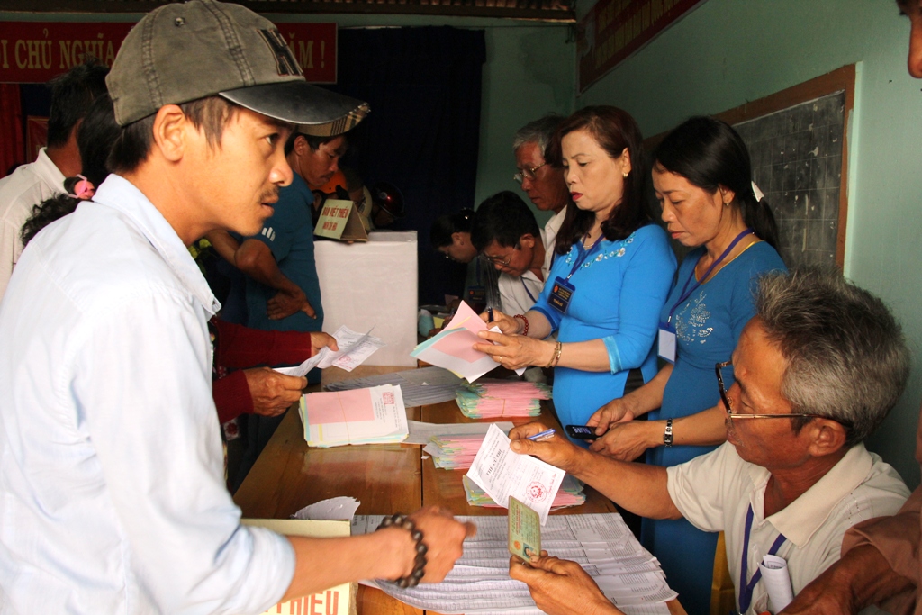 Cán bộ bầu cử kiểm tra thẻ cử tri và phát phiếu bầu cử cho cử tri tại tổ bầu cử số 10, xã Hòa Sơn