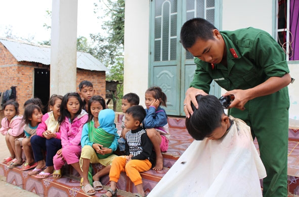 Chiến sĩ Bộ CHQS tỉnh hớt tóc cho trẻ em ở xã Ea Yiêng (huyện Krông Pắc).