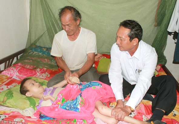 Ông Nguyễn Việt Tiến (bên phải), Chủ tịch Hội Chữ thập đỏ xã Ea Kao thăm hỏi  nạn nhân chất độc da cam thôn Cao Thắng.