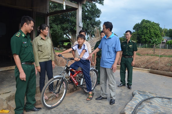     Thượng tá Nguyễn Hữu Phúc (thứ 2 từ phải sang) tặng  xe đạp cho cháu Trịnh Văn Sơn  (học sinh lớp 8 C, Trường THCS  Ea Bung, huyện  Ea Súp).