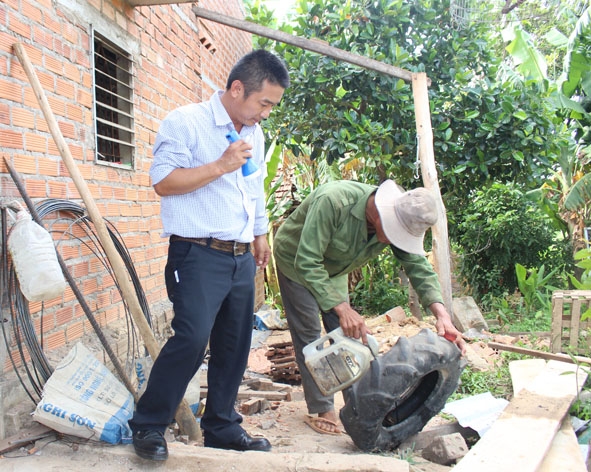 Cán bộ Trung tâm Y tế dự phòng tỉnh hướng dẫn người dân thôn 2, xã Ea Đar, huyện Ea Kar cách đổ nhớt vào lốp xe cũ  để loại bỏ lăng quăng.   Ảnh: Kim Oanh