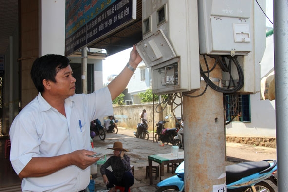 Ông Hồ Duy Vinh kiểm tra công tơ điện của một hộ kinh doanh do đơn vị quản lý. 