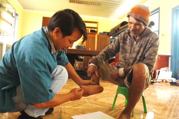 Anh Huỳnh Thanh Phong đang lấy số đo để may dép cho một bệnh nhân phong. 