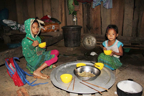 Em Sùng Thị Say đang ăn cơm để chuẩn đến trường. 