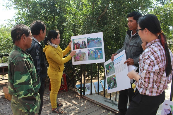 Đại diện nhóm phụ nữ bảo vệ  môi trường buôn  Jang Lành giới thiệu về sự  thay đổi trong  cuộc sống của người dân qua bộ ảnh Bên dòng Sêrêpốk. 