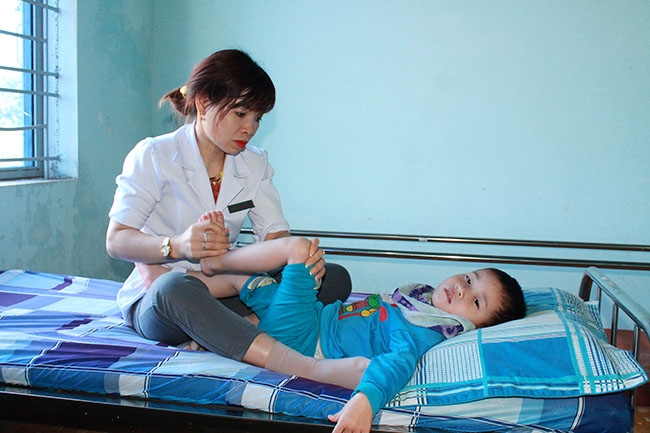 Nhân viên Phòng Y tế - phục hồi chức năng của Trung tâm Bảo trợ xã hội tỉnh tập vật lý trị liệu cho trẻ em khuyết tật. 