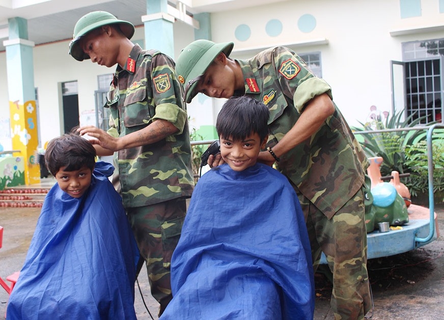 Chiến sĩ Tiểu đoàn 303 (Trung đoàn 584, Bộ Chỉ huy Quân sự tỉnh) cắt tóc miễn phí cho trẻ em.