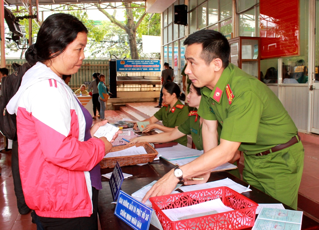 Trung tá Trần Bình Hưng hướng dẫn người dân làm thủ tục cấp đổi chứng minh nhân dân.
