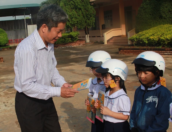 Ông Nguyễn Văn Hà,  Chủ tịch UBND huyện Ea Kar trao mũ  bảo hiểm  và sách  làm quen  với luật an toàn giao thông tặng học sinh Trường  Tiểu học Nguyễn Thị Minh Khai,  thị trấn Ea Kar.  