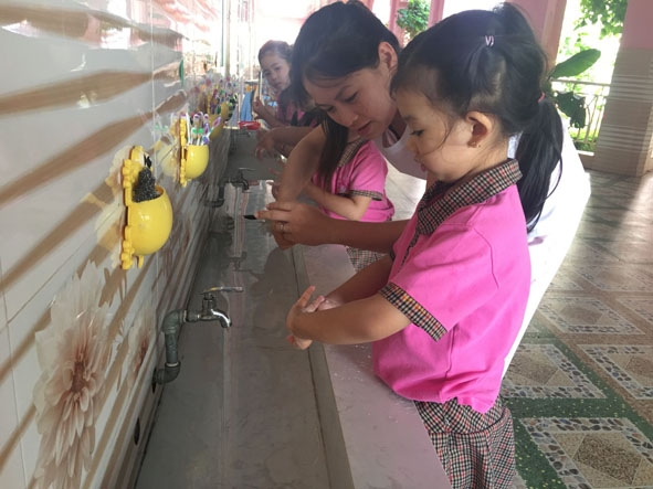 Giáo viên hướng dẫn trẻ rửa tay bằng xà phòng.