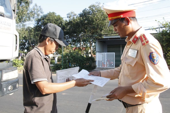 Cảnh sát giao thông Công an tỉnh kiểm tra giấy tờ của tài xế xe tải.